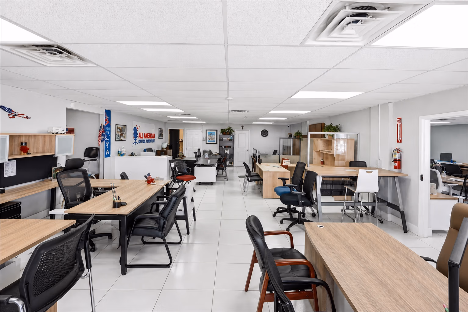 Rows of desks and office chairs displayed inside the All American Office Furniture showroom
